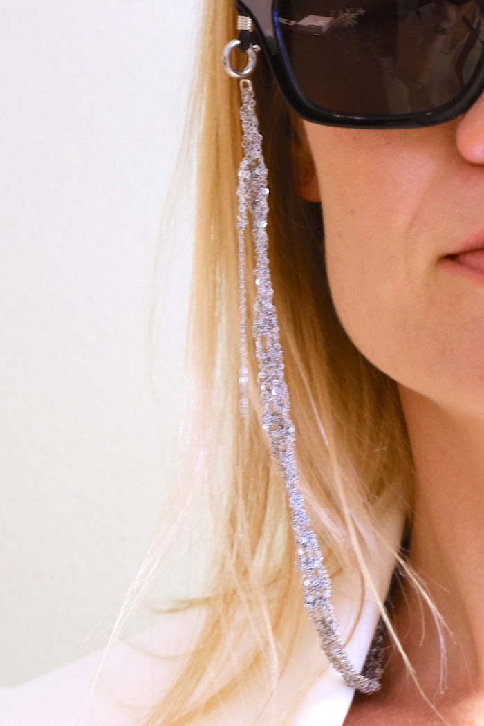 Person wearing sunglasses with a decorative chain hanging from the arm. Katia Alpha jewelry Barcelona studio