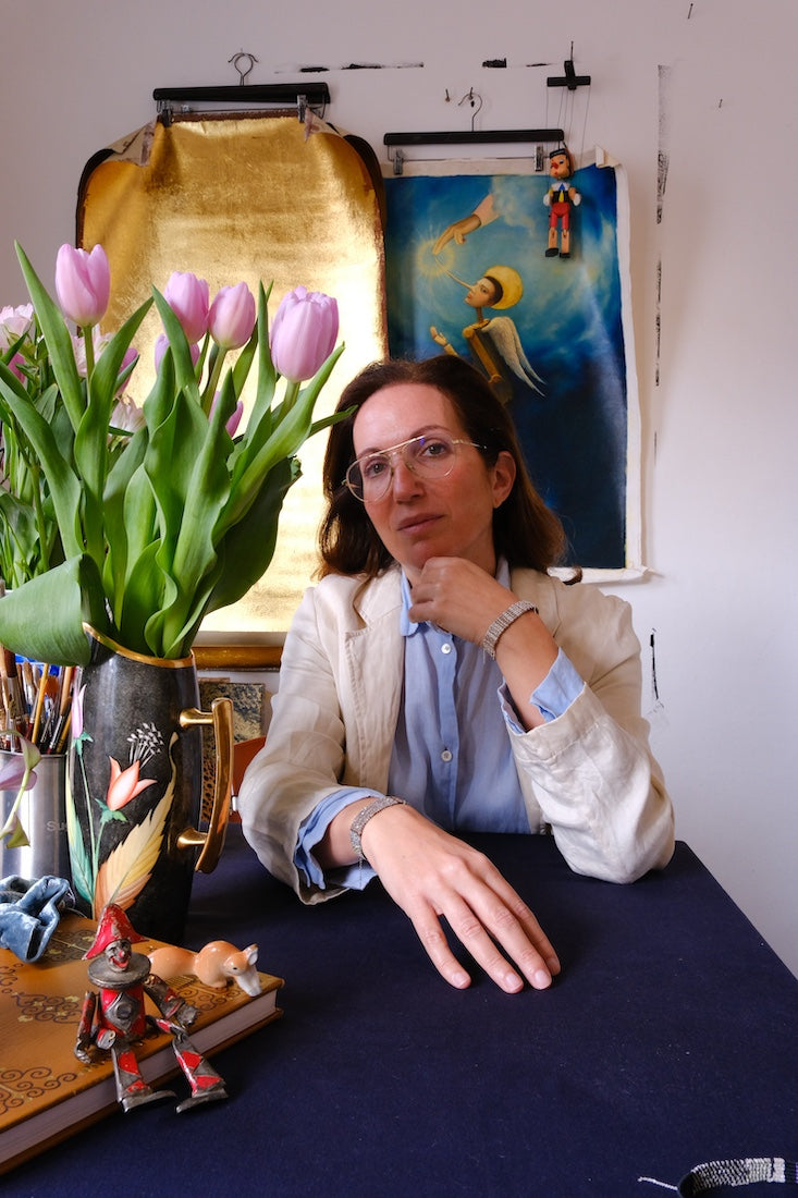 Woman sitting at a table with tulips and artwork in the background in Katia Alpha studio Spain

